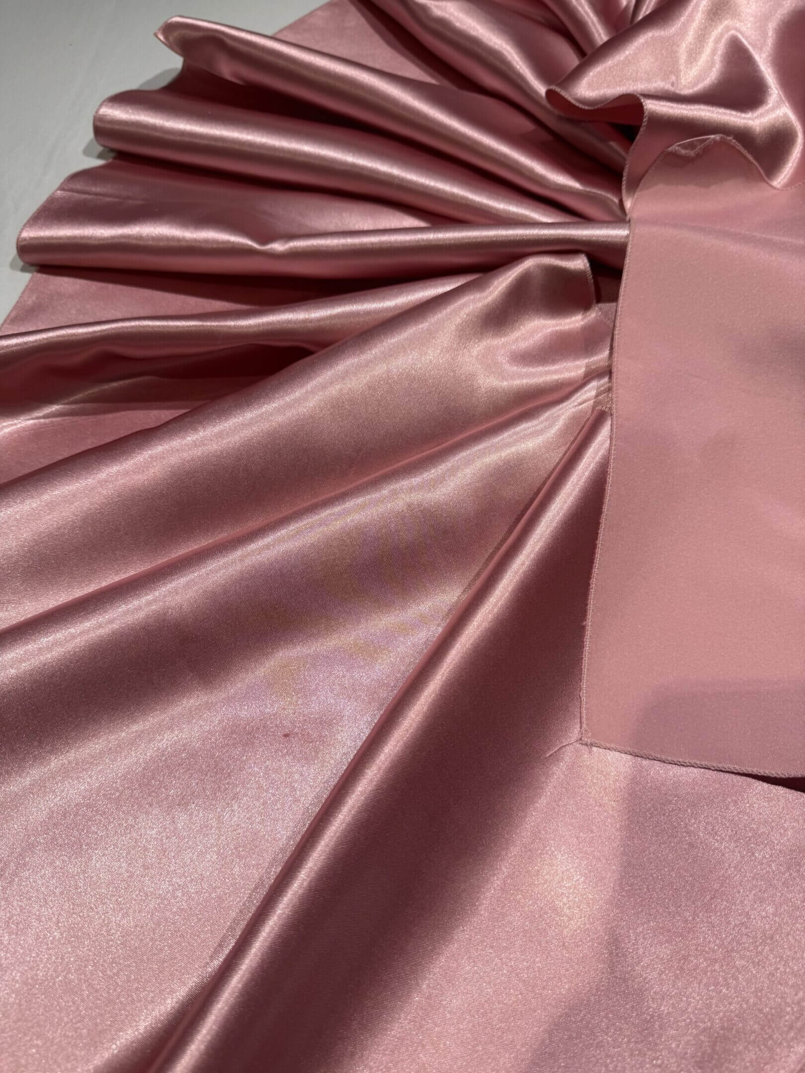 Smooth, shiny pink satin fabric with gentle folds.